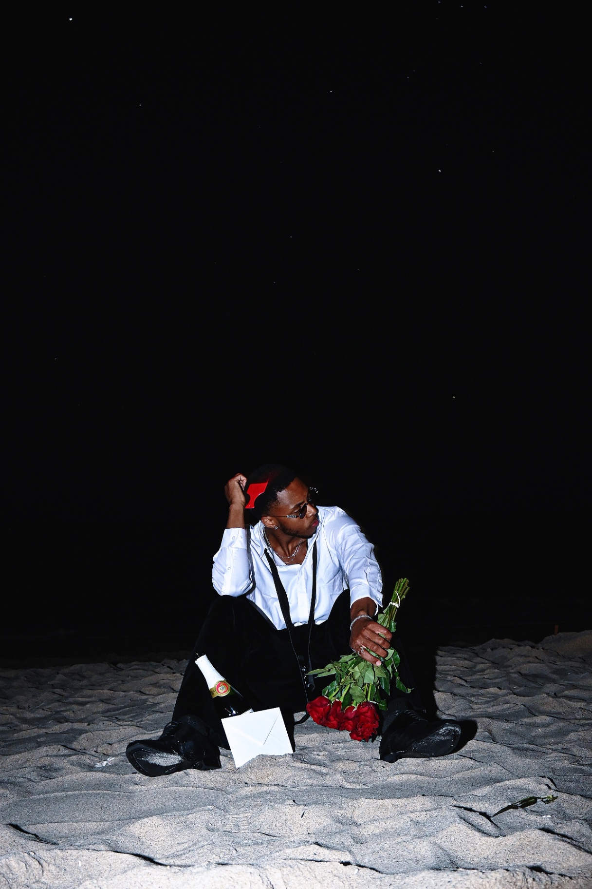 Saint Tailor seated on the beach with red roses