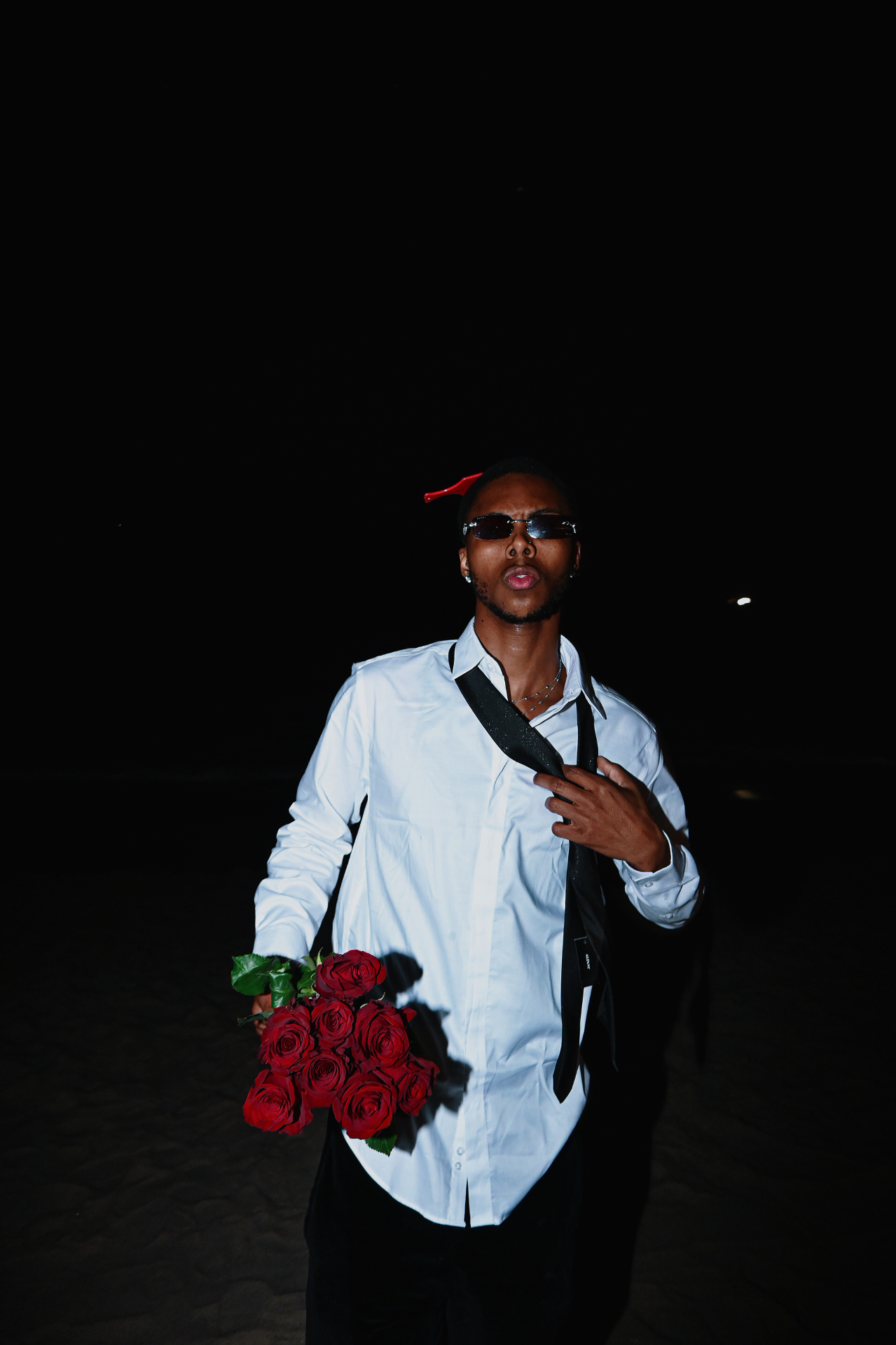 Saint Tailor standing on the beach with red roses